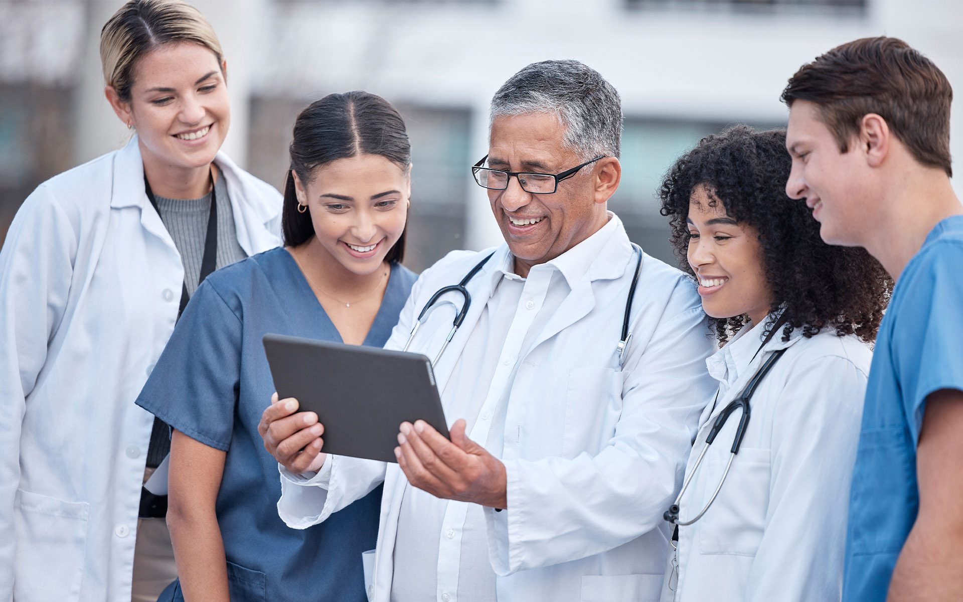 Unity Insurance | A MedChi Company - Group of Doctors Looking Over a Tablet Together